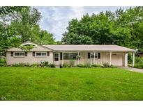 Charming single-story home with attached garage, well-maintained lawn, and colorful flowerbeds enhancing curb appeal at 10155 Orchard Park W Dr, Carmel, IN 46280