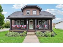 Charming two-story home with a covered front porch decorated with patriotic bunting and well-maintained landscaping at 514 E 2Nd St, Sheridan, IN 46069