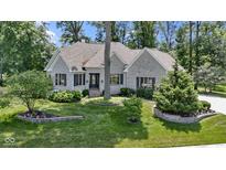 Charming stone home featuring manicured landscaping, a lush green lawn and mature trees at 10585 Golden Bear Way, Noblesville, IN 46060