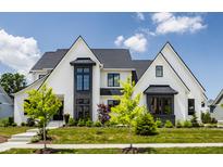 Stunning two-story home with white brick, black trim, a lush lawn, and beautiful landscaping at 12022 Otto Ln, Carmel, IN 46032