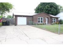 Cozy brick home featuring a metal roof, attached garage and chain link fence in front at 1504 Gwinn Ln, Lapel, IN 46051