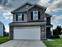 Two-story home featuring stone accents, a two-car garage, and a well-manicured front lawn at 19533 Chip Shot Rd, Noblesville, IN 46062