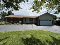 Charming brick ranch home with a well-maintained lawn, mature landscaping, and a two car garage at 4675 N Riverside Dr, Columbus, IN 47203