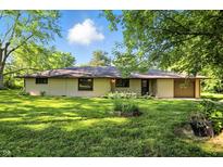 Charming ranch home features a well-manicured lawn, attached garage, and mature trees at 4765 E 200 N, Anderson, IN 46012