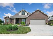 Charming brick home features a well-manicured lawn, attached two-car garage, and inviting covered front porch at 4909 N Graystone Dr, Muncie, IN 47304