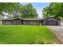 Charming single-story home with dark siding, well-maintained lawn and mature trees creating inviting curb appeal at 505 E Marion Ave, Arcadia, IN 46030