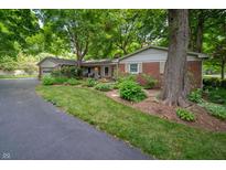 Charming brick home featuring mature trees and a well-manicured lawn and landscape at 7224 N Tuxedo St, Indianapolis, IN 46240