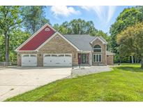 Charming brick home features a three-car garage and a well-maintained front yard with mature trees at 1066 N Dogwood Way, Greenfield, IN 46140