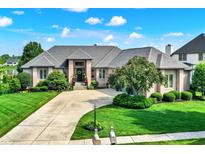 Stunning brick home featuring a grand entrance, manicured lawn, and a circular driveway on a sunny day at 14737 Macduff Dr, Noblesville, IN 46062