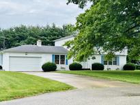 Charming two-story home with white exterior, blue shutters, attached garage, and mature trees at 32 W Northeast Ct, Shelbyville, IN 46176