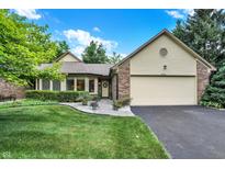 Charming brick home featuring an attached two-car garage, well-maintained lawn, and lush landscaping at 9578 Cadbury Cir, Indianapolis, IN 46260