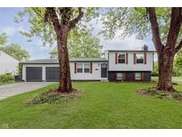 Charming split-level home featuring a well-manicured lawn, two-car garage, and mature trees at 1537 Mutz Dr, Indianapolis, IN 46229
