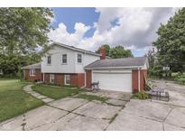Two-story home featuring a brick garage, partial brick facade, and concrete driveway at 1924 W 65Th Pl, Indianapolis, IN 46260