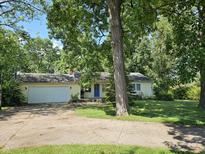 Charming home featuring an attached garage and welcoming blue front door surrounded by mature trees at 2024 E 41St St, Anderson, IN 46013
