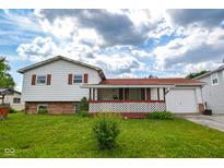 Charming two-story home with a red roof, white siding, covered front porch, and a lush front lawn on a sunny day at 2520 Tesh Dr, Indianapolis, IN 46203