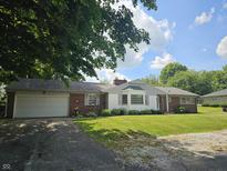 Charming brick home features a lush front yard, attached garage, and a mix of architectural styles at 308 N Edgeway Dr, Alexandria, IN 46001