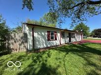 Quaint single-story home with a lawn and white exterior featuring red trim around the windows and gutters at 4014 Arquette Dr, Indianapolis, IN 46235