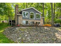 Charming brick home featuring a lakeside patio and serene views surrounded by lush trees at 6300 Grouse Dr, Nineveh, IN 46164