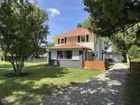 Charming two-story home features a red roof, landscaped yard, and a long gravel driveway at 4106 N Sherman Dr, Indianapolis, IN 46226