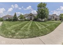 Charming home with a manicured lawn, mature trees, and an inviting entrance, set against a backdrop of blue skies and puffy clouds at 3270 Cherokee Cir, Bargersville, IN 46106