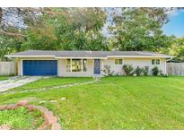 Charming single-story home featuring a blue door and garage against a lush green lawn and mature trees at 7643 S Delaware St, Indianapolis, IN 46227
