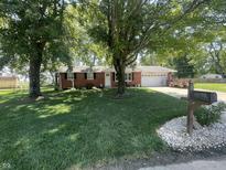 Charming brick ranch home with mature trees and a lush green lawn in a serene neighborhood at 9783 Lee Ct, Columbus, IN 47203