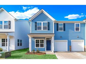 Two-story light blue home with white garage door and landscaping at 718 Nw Palm Frond Way # 66, Calabash, NC 28467