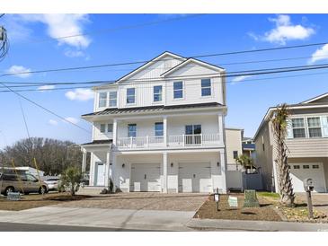 Inviting three-story white home with a double garage and charming balcony, set against a clear blue sky at 2401 Duffy St., North Myrtle Beach, SC 29582