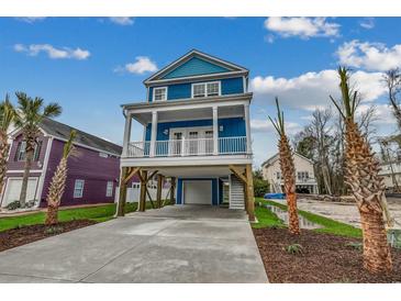 Charming blue two-story home with a covered porch, spacious driveway, and lush landscaping at 723 10Th Ave. S, Surfside Beach, SC 29575