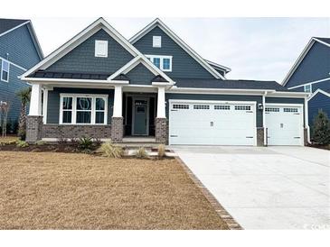 Two-story home with gray siding, brick accents, and a three-car garage at 2369 Vera Way, Longs, SC 29568