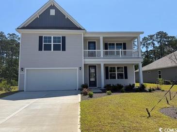 Charming two-story home featuring a covered porch, a two-car garage, and professional landscaping at 121 Fair Meadow Ct., Loris, SC 29569