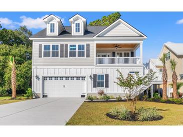 Charming two-story home featuring a covered porch, dormer windows, and a two-car garage with beautiful landscaping at 132 Oak Bay Dr., Georgetown, SC 29440