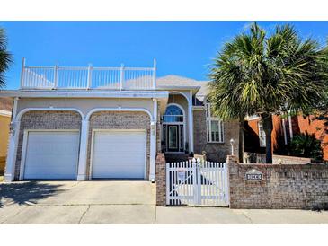 Beautiful two-story brick home with a white fence and a well-manicured lawn and roof top deck at 144 Waterway Crossing Ct., Little River, SC 29566