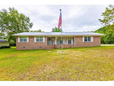 Charming single-story brick home featuring a metal roof and a spacious front yard with mature trees at 705 White Oak Dr., Johnsonville, SC 29555