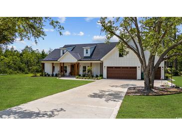 White farmhouse exterior with brown garage doors, landscaping, and long driveway at 2192 Eastwoods Dr., Conway, SC 29526