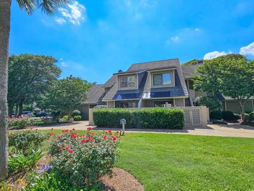 Charming two-story home with beautiful landscaping, including roses and mature trees, creating a welcoming curb appeal at 122 Hartland Dr. # 11-D, Myrtle Beach, SC 29572