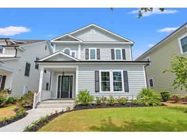 Charming two-story home with a welcoming porch, manicured lawn, and classic architectural details under a blue sky at 219 West Palms Dr., Myrtle Beach, SC 29579