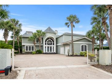 Stunning two-story home features a brick driveway, towering palm trees, and a grand entrance at 8000 Beach Dr., Myrtle Beach, SC 29572