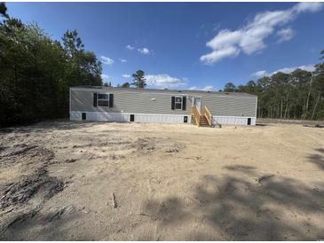 Newly constructed single story home with gray siding and stairs to the front entrance in a wooded area at 2500 Newton Rd., Aynor, SC 29511