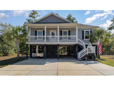 Inviting two-story home featuring gray siding, white columns and railings, and a spacious carport at 100 Lure Ct., Conway, SC 29526