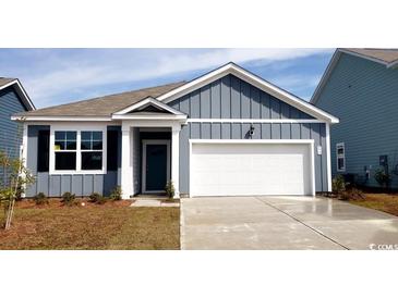 Charming single-Gathering home showcasing blue siding, a white garage door, and manicured landscaping at 572 Duvall St., Longs, SC 29568