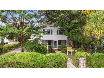 Charming two-story home with white siding, screened porch, and lush landscaping, creating curb appeal at 412 29Th Ave. N, Myrtle Beach, SC 29577