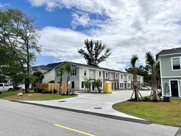View of townhomes featuring light green and white color schemes, sidewalks, and a spacious parking lot at 6306 Somerset Dr., Myrtle Beach, SC 29572