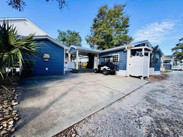 Charming blue home with a covered patio featuring yellow chairs, plus a convenient golf cart and spacious driveway at 6001 - N21 S Kings Hwy., Myrtle Beach, SC 29575