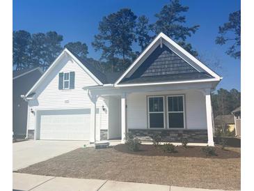 Charming single-story home featuring a two-car garage, white siding, and attractive stone accents at 1209 Nw Calabash Station Blvd., Calabash, NC 28467