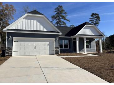 Charming one-story home featuring a two-car garage, stone accents, and a well-manicured lawn under a clear blue sky at 216 Palmetto Sand Loop, Conway, SC 29527