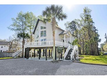 Stunning raised beach house featuring a spacious deck, palm trees and stairs leading to ground level at 5800 Creekside Dr., Myrtle Beach, SC 29588