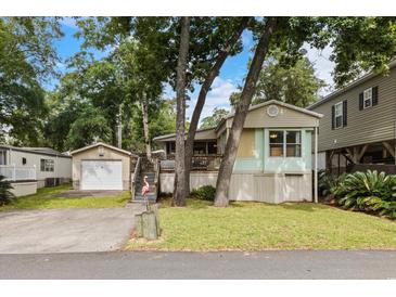 Charming home with a detached garage, driveway, and a well-maintained lawn, enhanced by a pink flamingo statue at 6001-Mh107 S Kings Hwy., Myrtle Beach, SC 29575