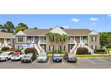Exterior view of a two-story condo building with palm trees, white stairs and parking at 1137 Peace Pipe Ln. # 201, Myrtle Beach, SC 29579