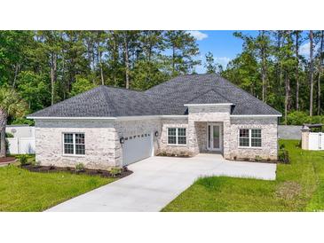 Charming brick home featuring a well-manicured lawn and attached two-car garage at 205 Waterfall Circle, Little River, SC 29566